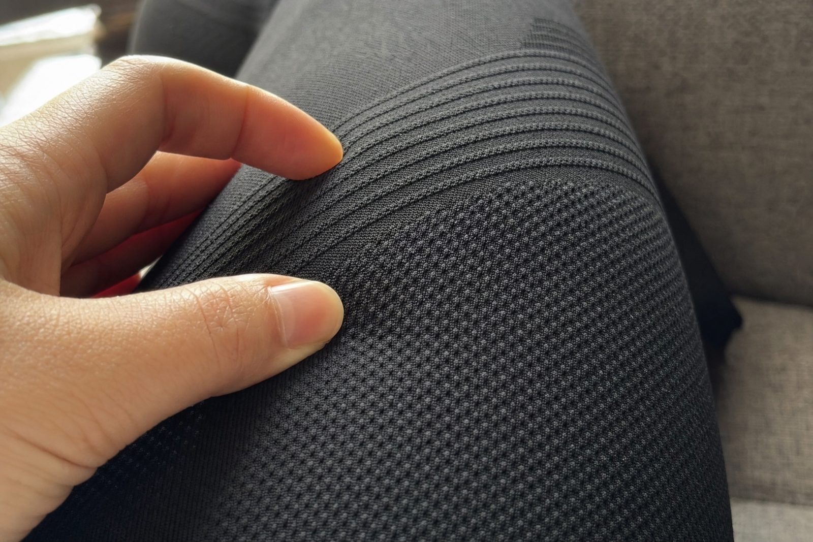 Fingertips pressing into the soft raised knit of black compression leggings